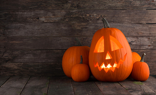 Glowing Halloween pumpkin heads jack o lantern on wooden background