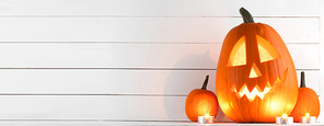 Halloween pumpkin heads jack o lantern and candles on white wooden background