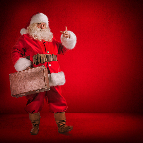 Christmas: Santa Claus Standing With Travel Bag with Gits on red background