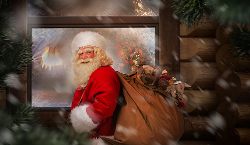 Santa Claus carrying his sack near wooden house at night outdoor. Christmas eve