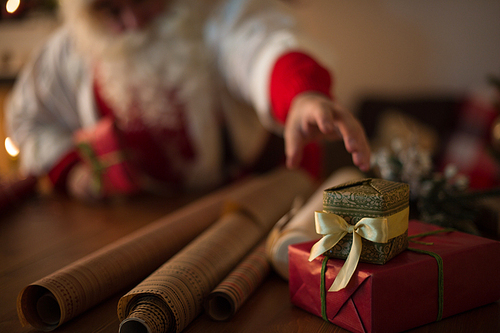 Santa Claus at Home wrapping christmas gifts