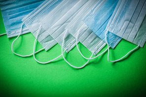 Disposable surgical masks on green background medicine concept.