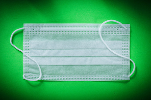 Disposable sterile face mask on green background.