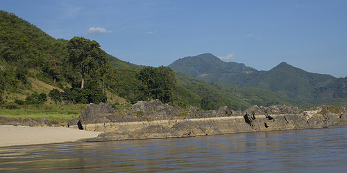 Scenic view of riverbank with mountain range in background, River Mekong, Sainyabuli Province, Laos