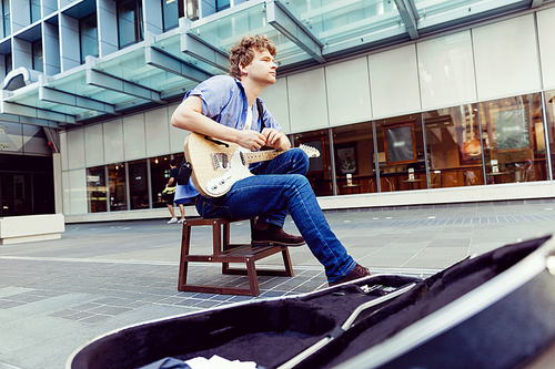 Portrait of young musician with guitar in city