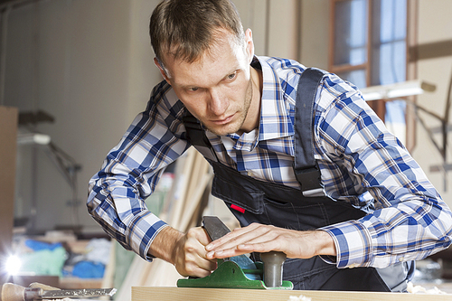 Carpenter working with plane in his studio