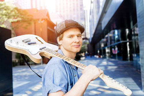 Portrait of young musician with guitar in city