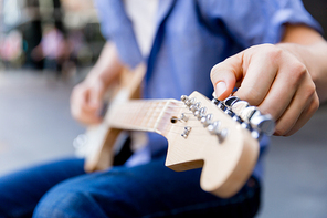 Hands of musician tuning his guitar outside