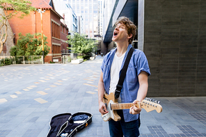 Portrait of young musician with guitar in city