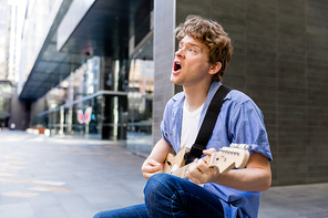Portrait of young musician with guitar in city