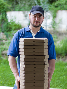 pizza delivery  portrait of a young deliverers with lots of stacked boxes of pizza in hands