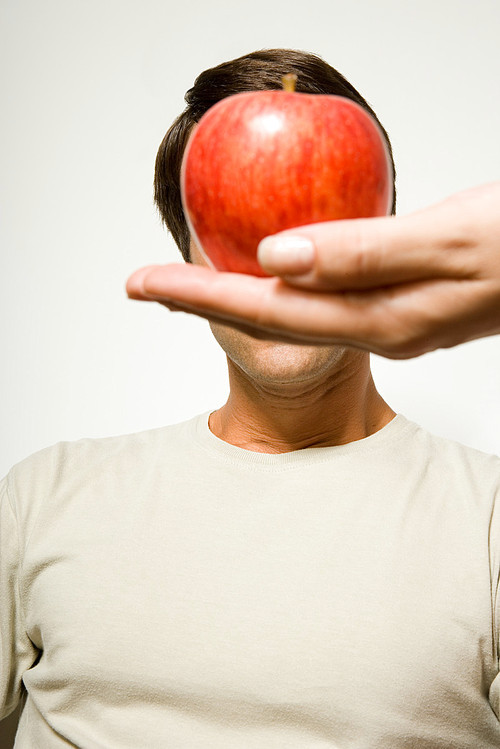 Woman holding apple over man's face