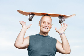 Senior man with a skateboard on his head