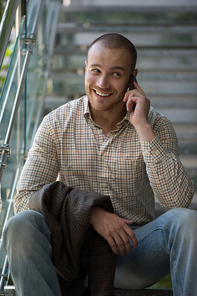 Businessman sitting on stairs at office building and talking by phone