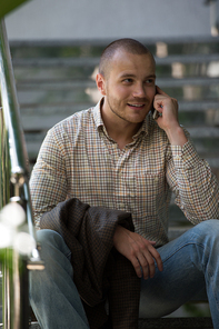 Businessman sitting on stairs at office building and talking by phone