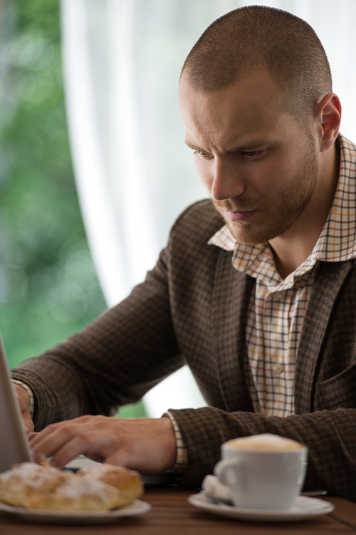 Young businessman working at cafe using laptop