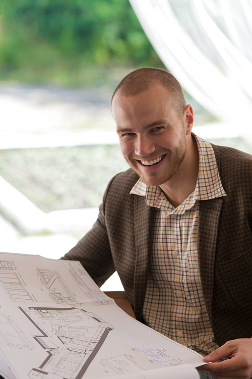 Happy businessman working with blueprint at sidewalk cafe