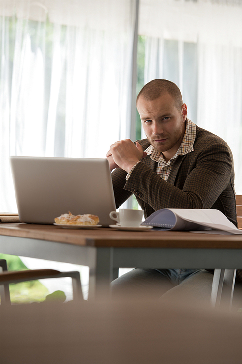 Young businessman working at cafe using laptop