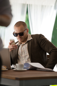 Handsome businessman talking on the phone in a cafe