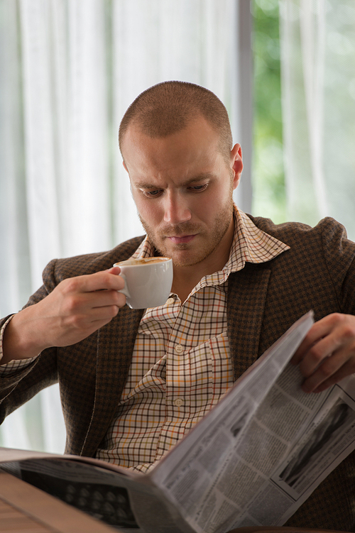 Pensive businessman reading a newspaper in cafe