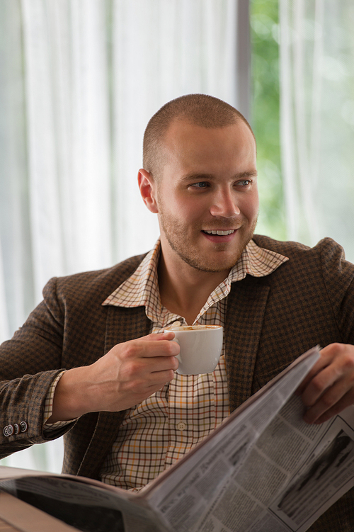 Pensive businessman reading a newspaper in cafe