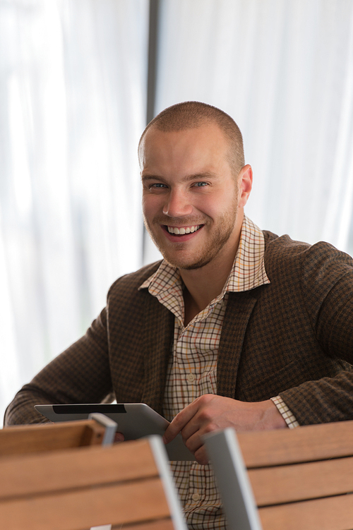 Young businessman on a coffee break. Using tablet computer.