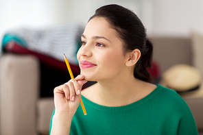 people and portrait concept - happy young woman with pencil thinking