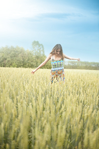 Happy woman walking arms open in a green meadow