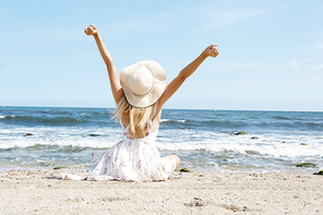 Blonde woman enjoy the sunny beach arm streatched. Travel concept
