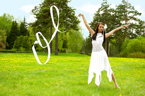 Closeup portrait of young pretty gymnast woman outdoor in summer park wearing white dress dancing and doing sports