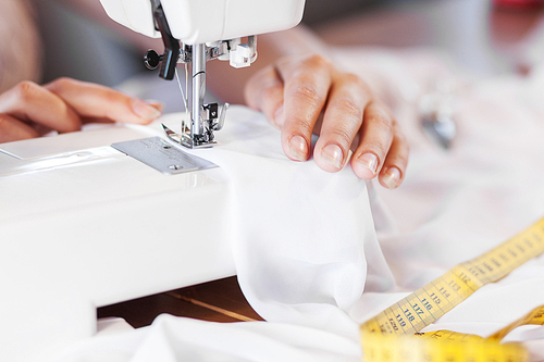 Close up of woman dressmaker hands working with sewing machine