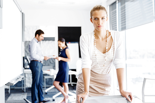 Attractive female woman in office with colleagues on background