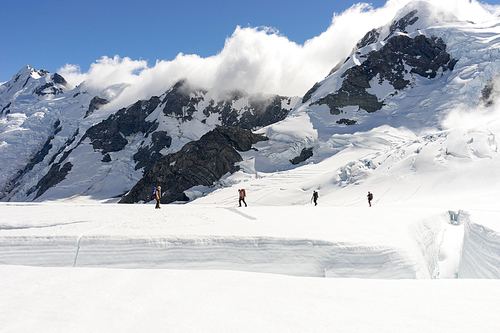 Group of people walking among snows of New Zealand mountains