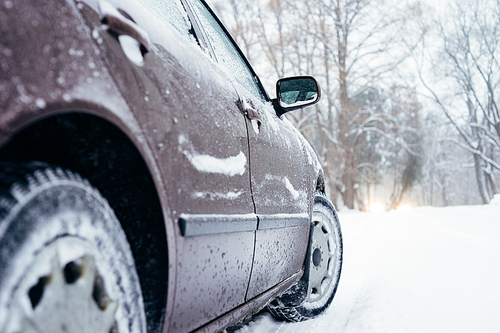 Car on winter road covered with snow. From ground view, selective focus