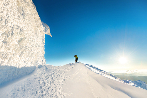 People on the top of the winter mountain in snow at sunset