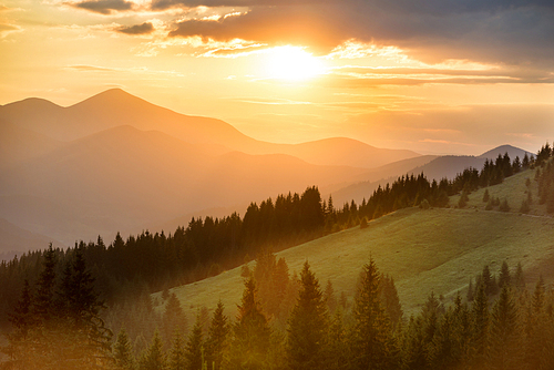 Beautiful dramatic sunset in the mountains. Landscape with sun shining through orange clouds