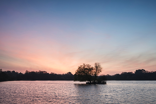 Beautiful Spring sunrise over calm lake in English countryside