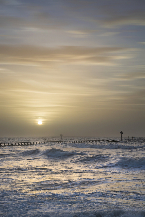 유토이미지 | Beautiful moody stormy landscape image of waves crashing onto beach at sunrise