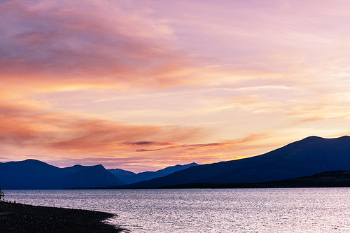 Serene scene by the mountain lake in Canada with reflection of the rocks in the calm water.