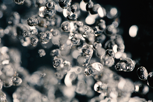 Macro shot of water drops frozen in the air, levitating on dark background