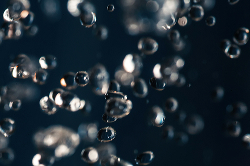 Small water drops frozen in an air on dark blue background