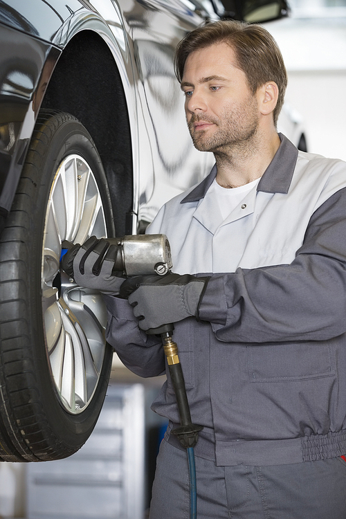 Repairman adjusting car's wheel in workshop