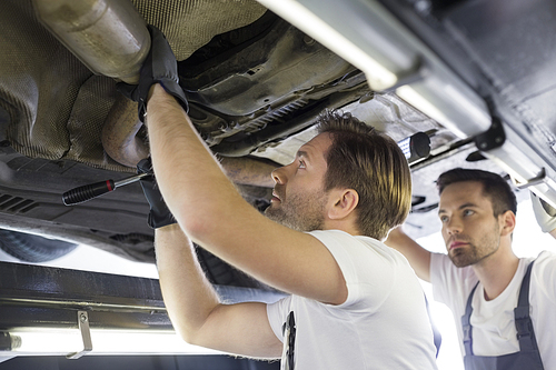 Male repair workers examining car in workshop