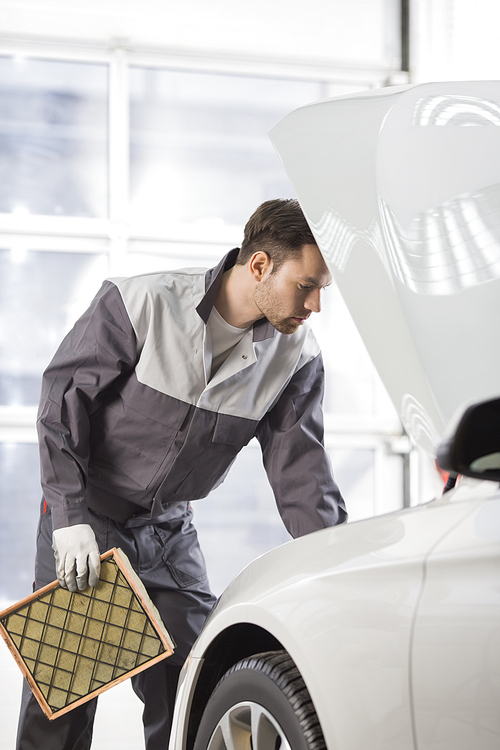 Young automobile mechanic examining car in automobile shop