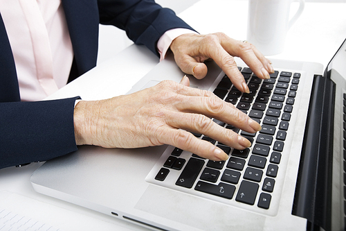 Cropped image of senior businesswoman typing on laptop