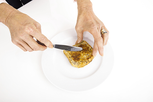 Businesswoman's hands spreading butter on bread