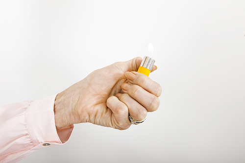 Businesswoman's hand holding cigarette lighter with flame in office