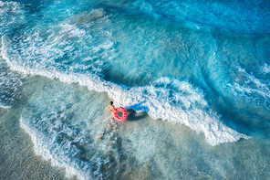 aerial view of slim young woman swimming on the donut swim ring in the transparent blue sea with waves at . tropical aerial landscape with girl, clear water, sunlight. top view. summer travel