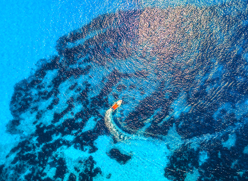 Aerial view of floating speed boat in transparent blue water. Motorboat in the sea in balearic islands at sunset in summer.  Landscape. Top view from drone. Seascape with yacht in motion in bay