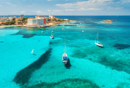 Boats and luxury yachts in transparent sea at sunset in summer in Mallorca, Spain. Aerial view. Colorful landscape with bay, azure water, sandy beach, blue sky. Balearic islands. Top view. Travel